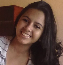 Sandra Lemos dos Santos sorrindo, com cabelo castanho longo e blusa listrada clara em ambiente interno