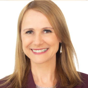 Fotografia de Alice Bianchini em fundo branco. Mulher adulta sorrindo, pele clara, cabelo liso loiro-escuro na altura dos ombros, com risca lateral. Usa brinco comprido e roupa em tom vinho, com colar prateado.