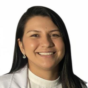 Fotografia de Tamyres Tomas em fundo branco: mulher adulta sorrindo, pele morena clara, cabelo longo preto liso com risca lateral. Usa brinco pequeno e veste jaleco branco sobre blusa clara de gola alta.